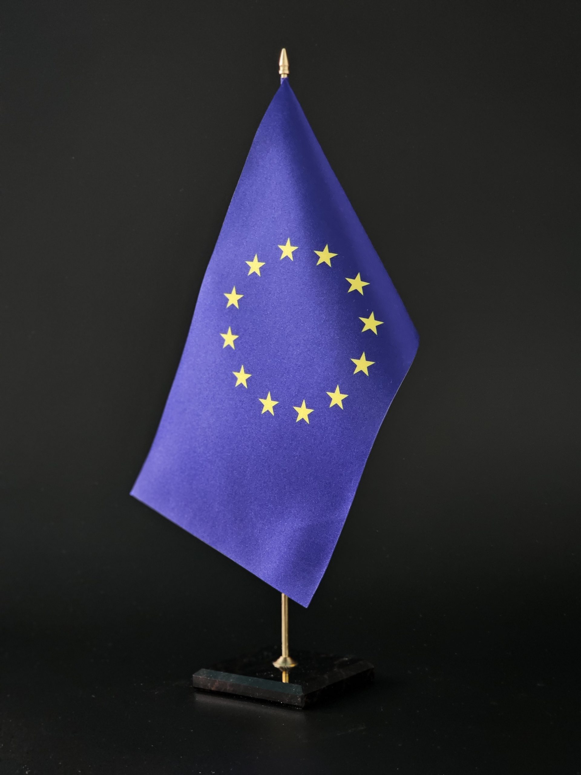 mala flaga jest trzymana przez reke i czarne tlo